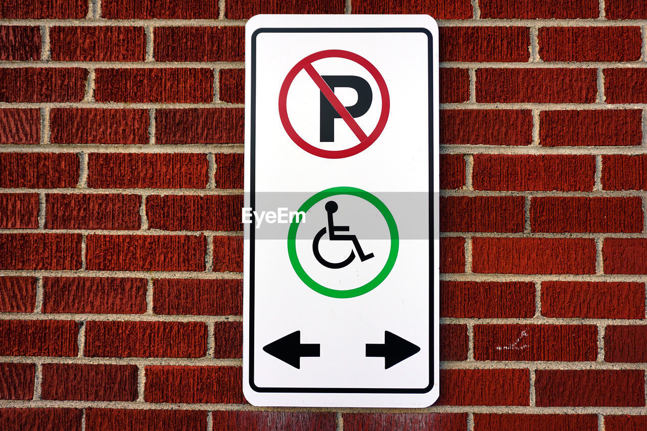 Close-up of wheelchair access sign on brick wall