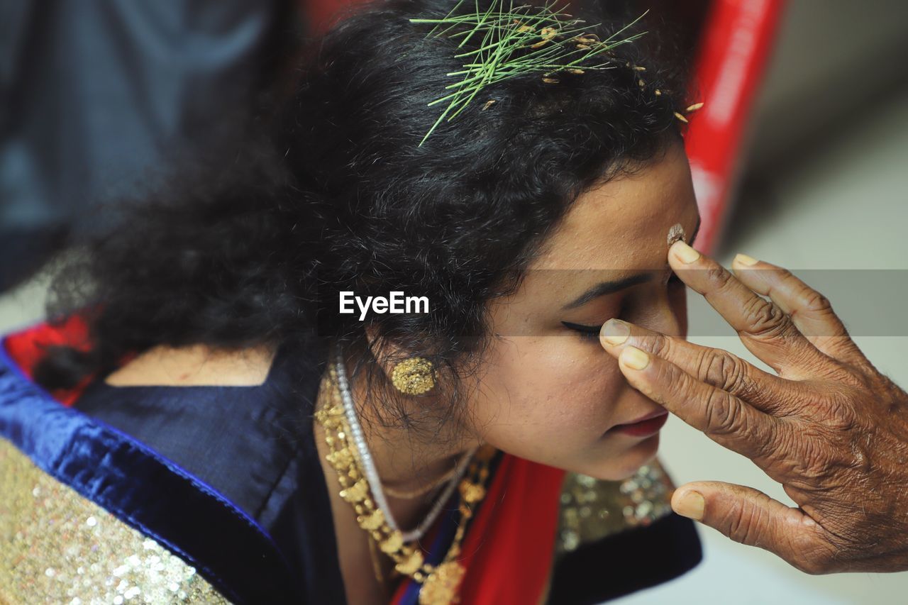 Cropped hand applying tilaka on woman forehead