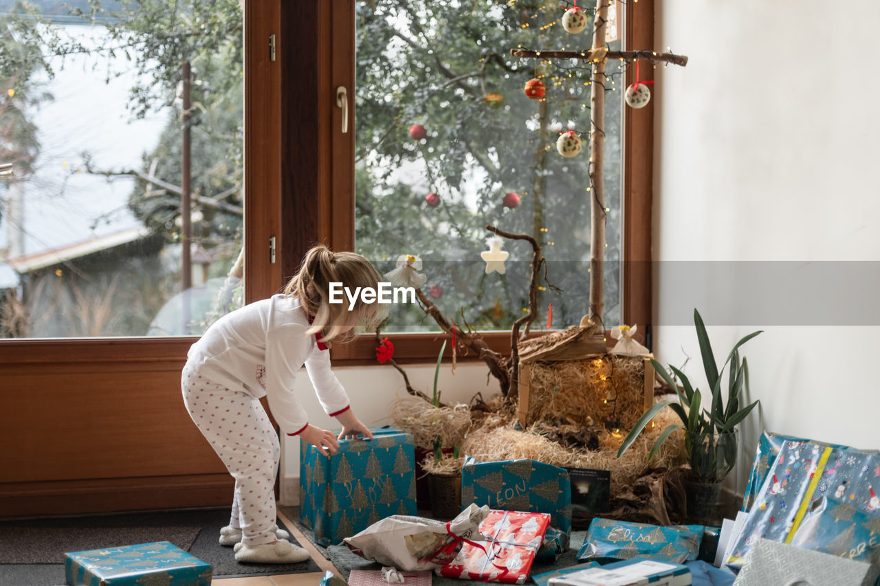 Side view of girl arranging christmas presents at home