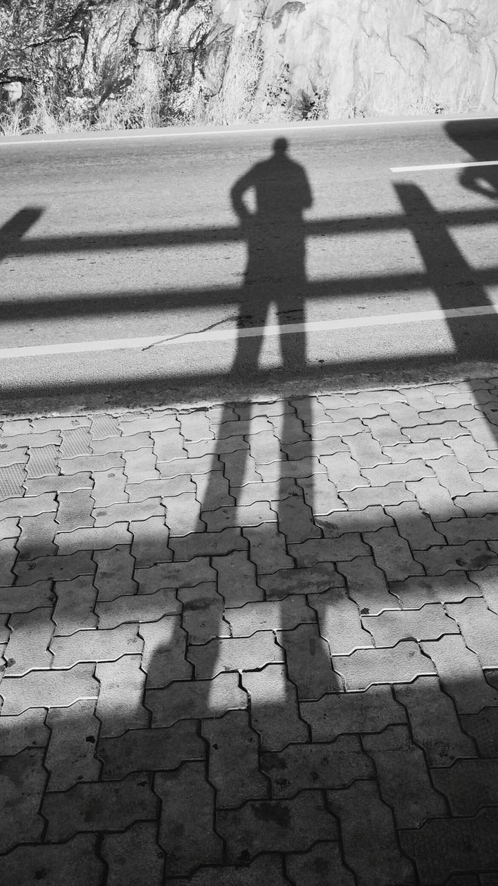 Shadow of man on cobblestone street