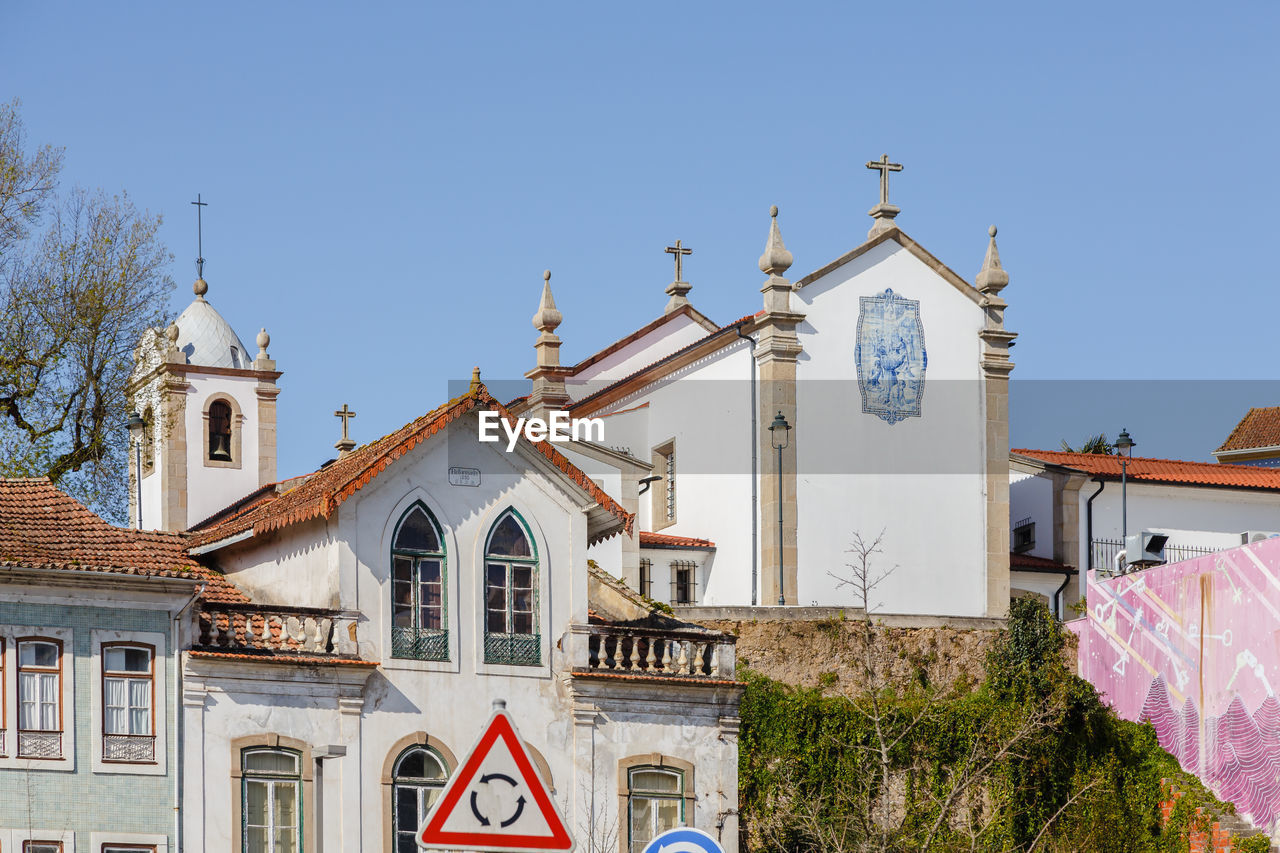 architecture, building exterior, built structure, place of worship, building, religion, belief, sky, town, nature, travel destinations, spirituality, clear sky, no people, blue, facade, day, catholicism, sunny, landmark, city, tourism, travel, history, plant, outdoors, the past, tower, clock, tree