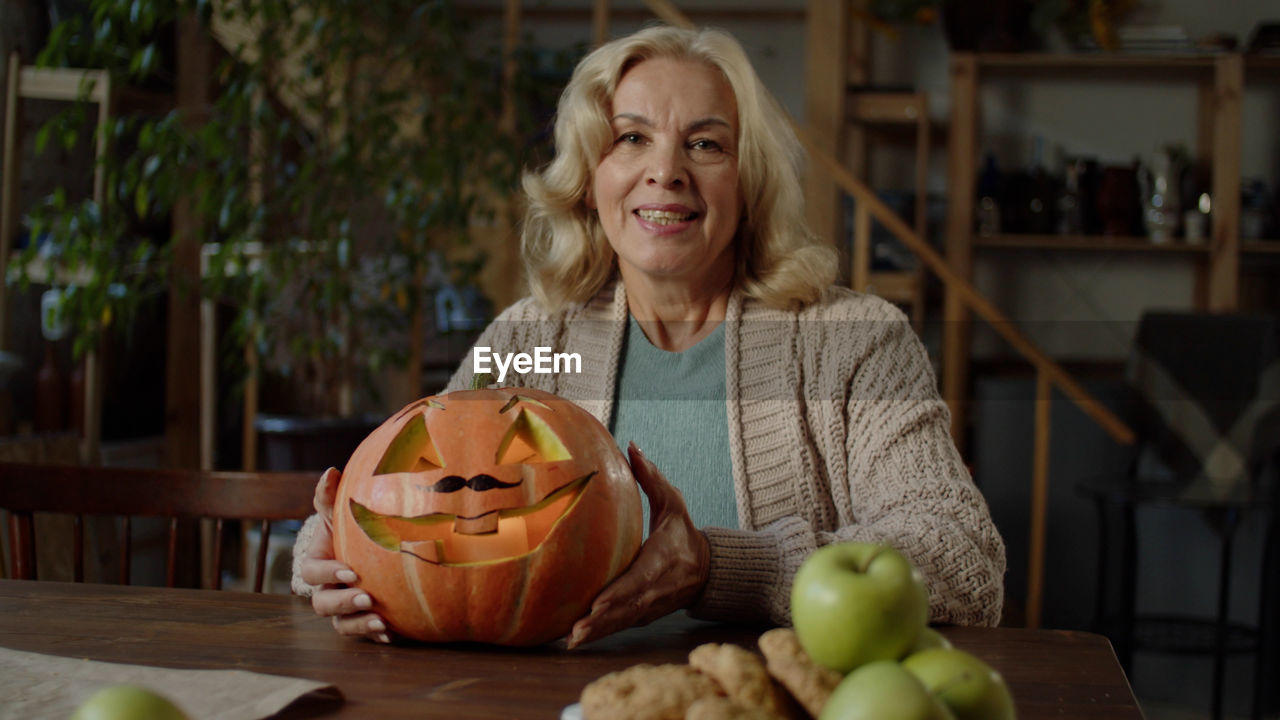 portrait of young woman holding pumpkin in plate