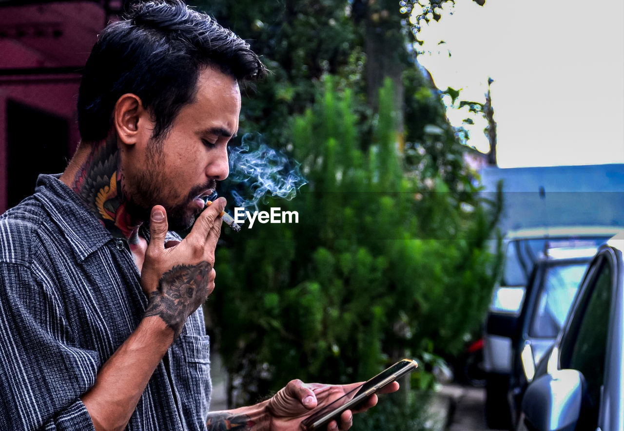 Young man looking away while using mobile phone