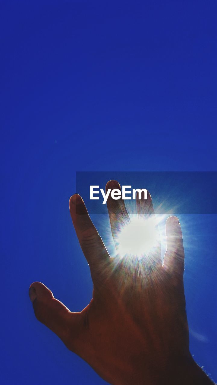 Low angle view of hand against clear blue sky