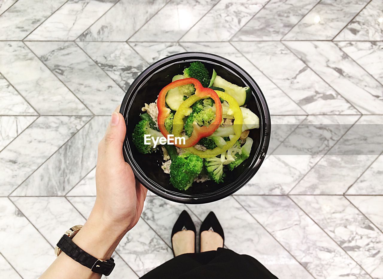 Low section of woman holding salad in bowl