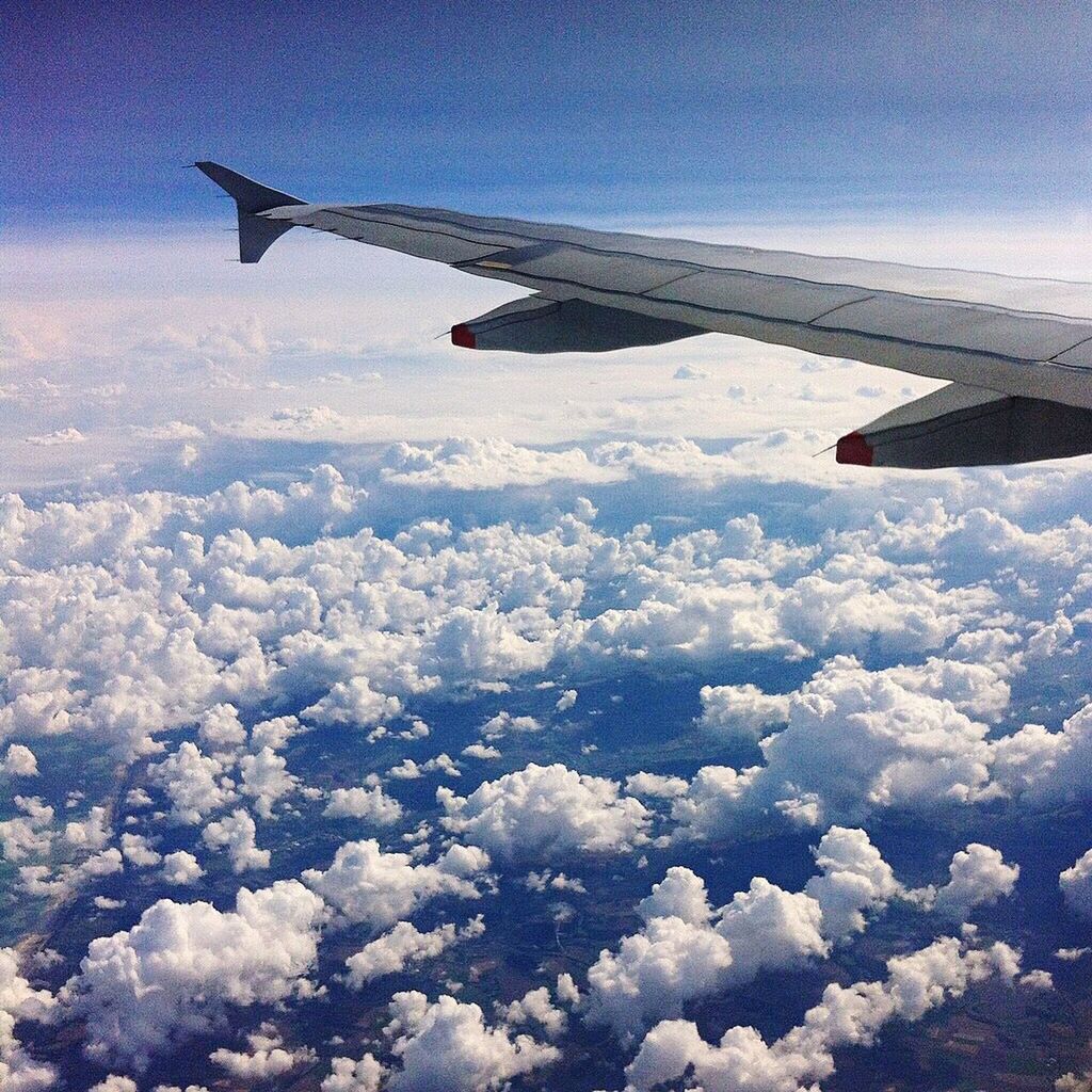 AIRPLANE WING FLYING OVER CLOUDS