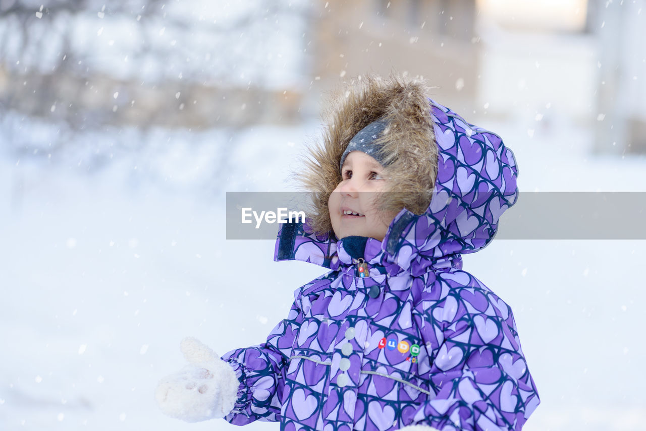 Girl standing on snow covered field during snowfall