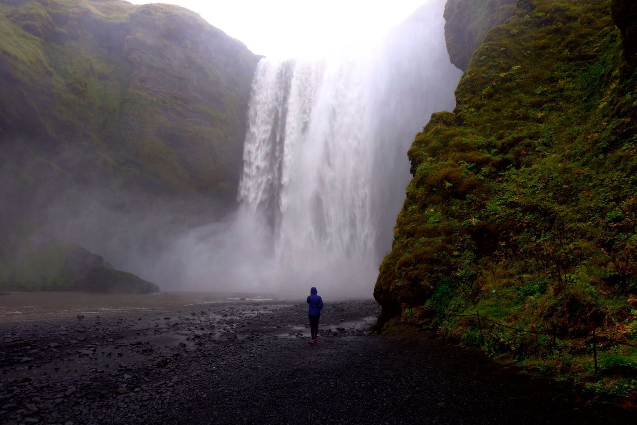 Rear view of mid adult woman looking at waterfall