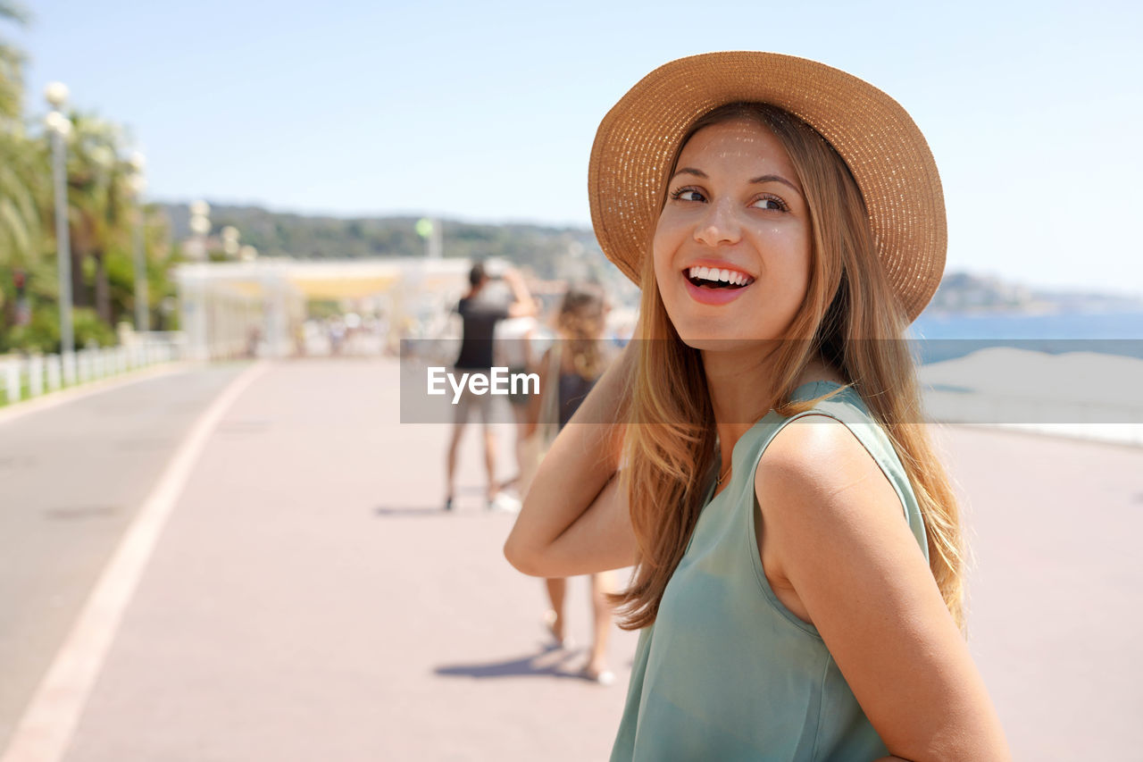 Close-up of stylish girl turns around and looks back on promenade des anglais, nice, france