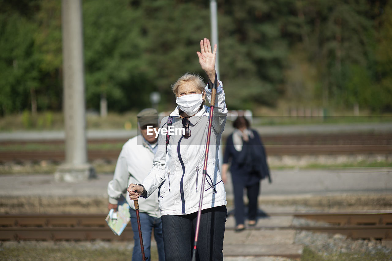 A group of senior travelers with masks on their faces cross the railway tracks