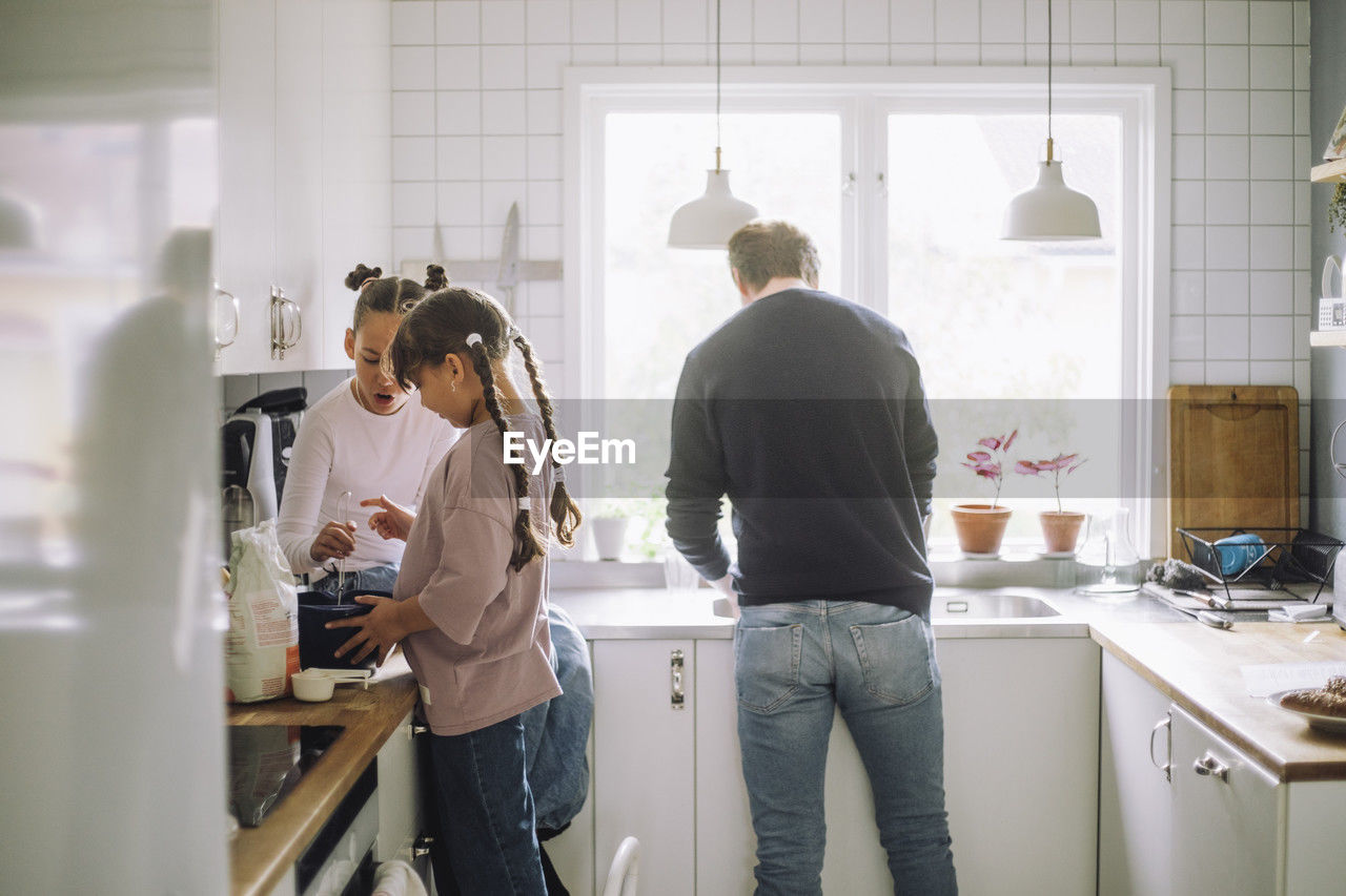 Siblings preparing food with father working in kitchen at home