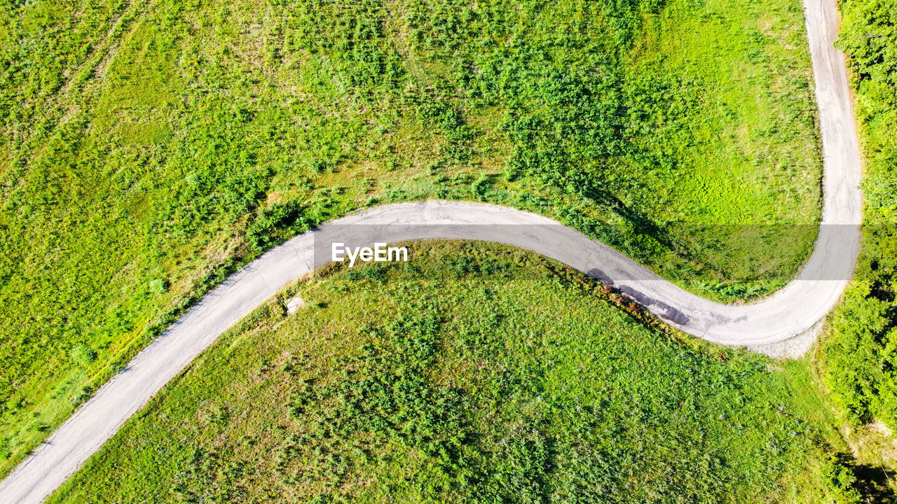 HIGH ANGLE VIEW OF ROAD PASSING THROUGH A FIELD