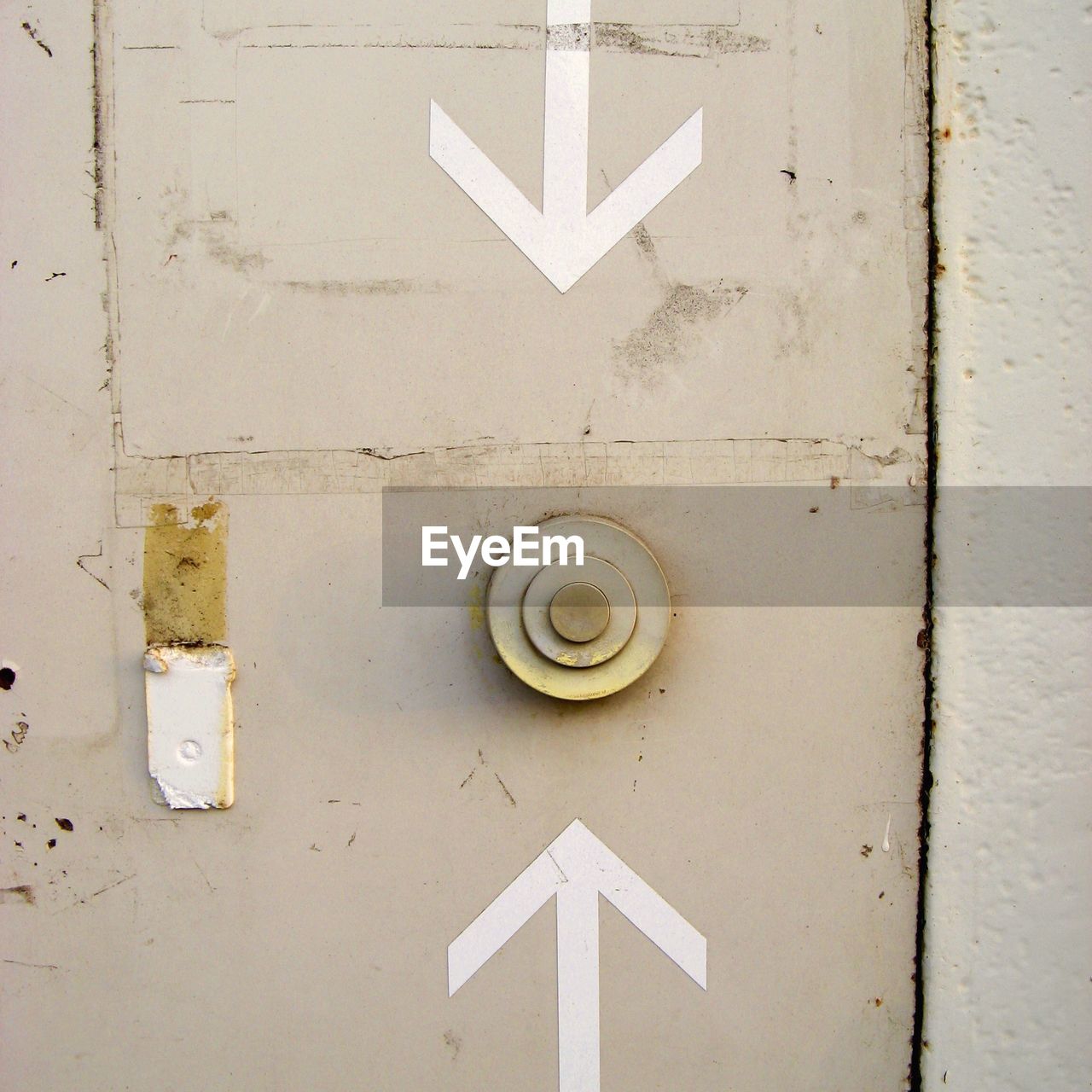 Push button amidst arrow symbols on wall