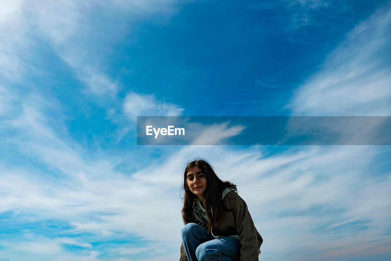 Portrait of smiling young woman against blue sky