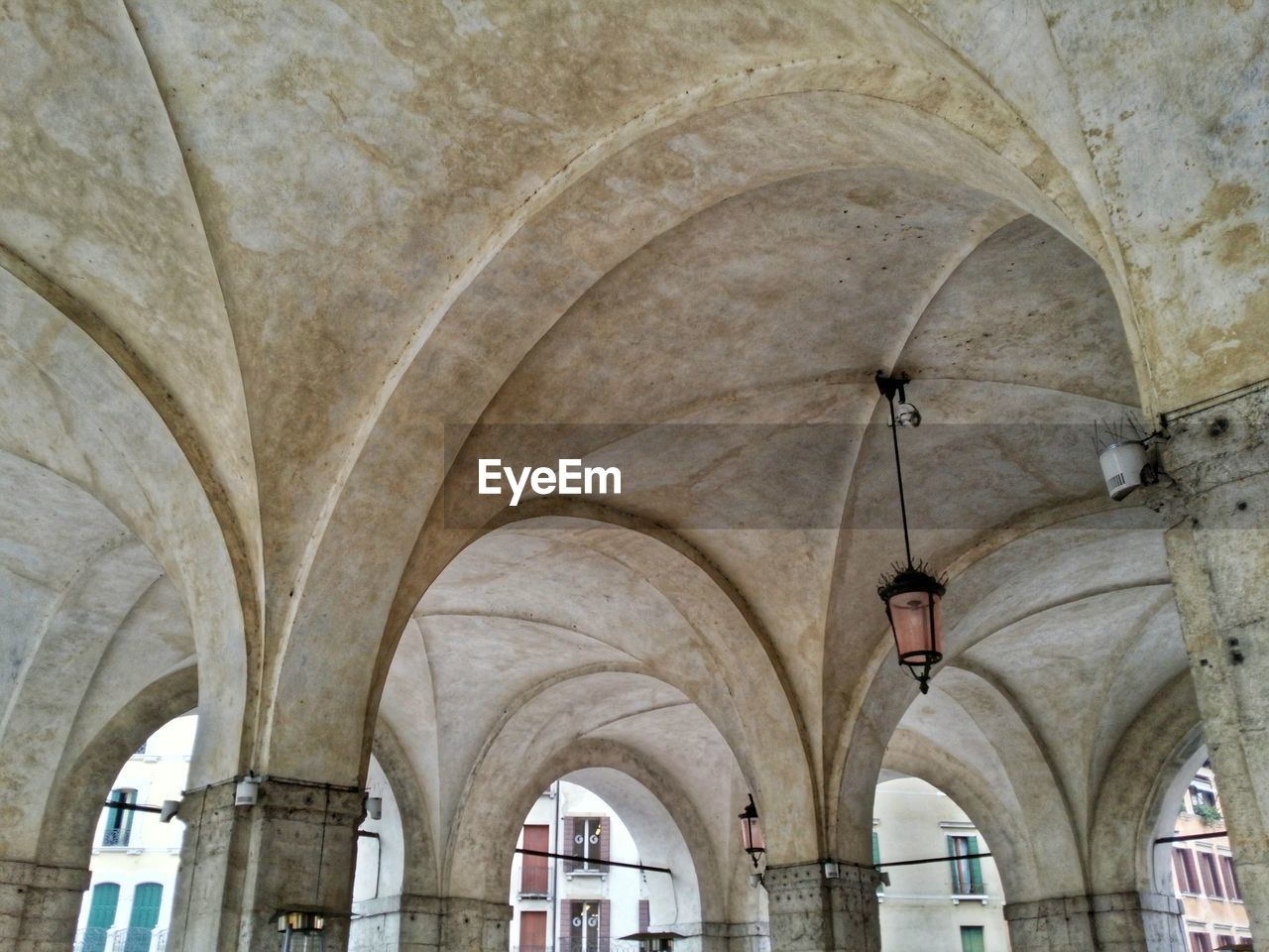 Low angle view of old lamp hanging from historic building ceiling