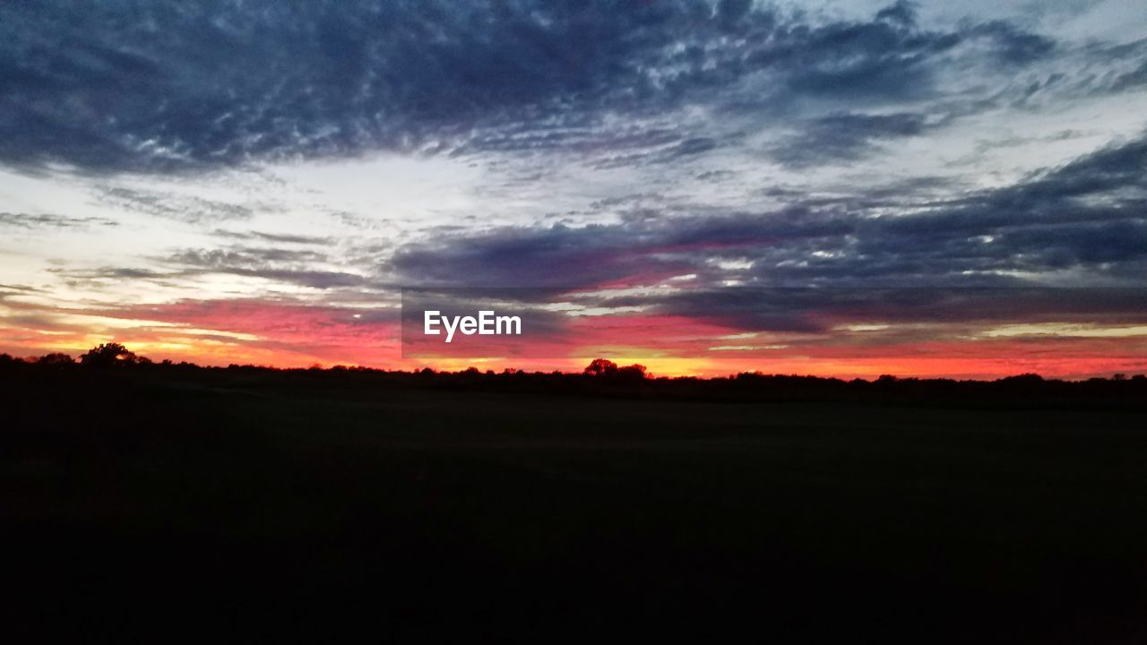 SILHOUETTE LANDSCAPE AGAINST DRAMATIC SKY DURING SUNSET