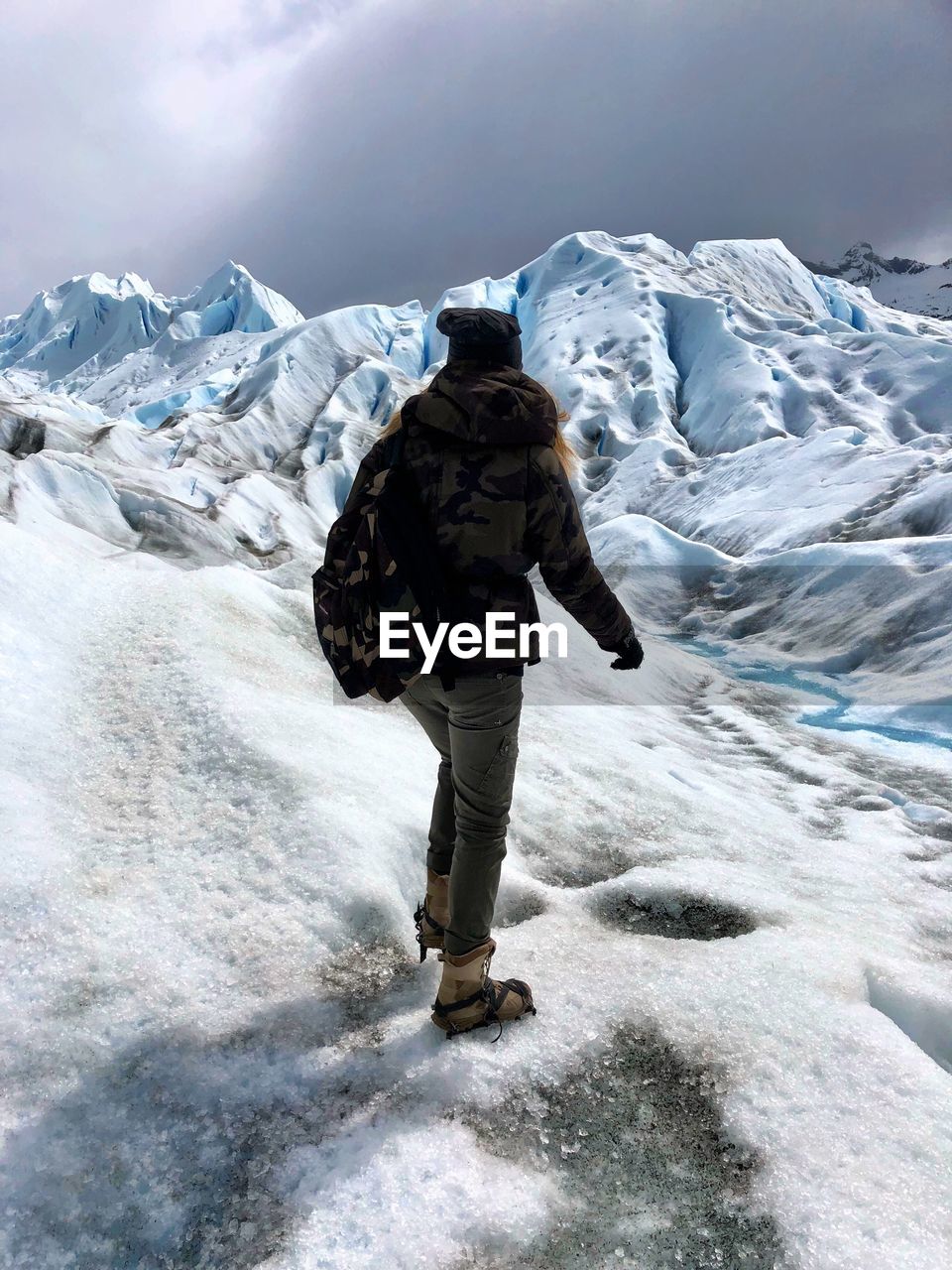 Rear view of woman standing on glacier 