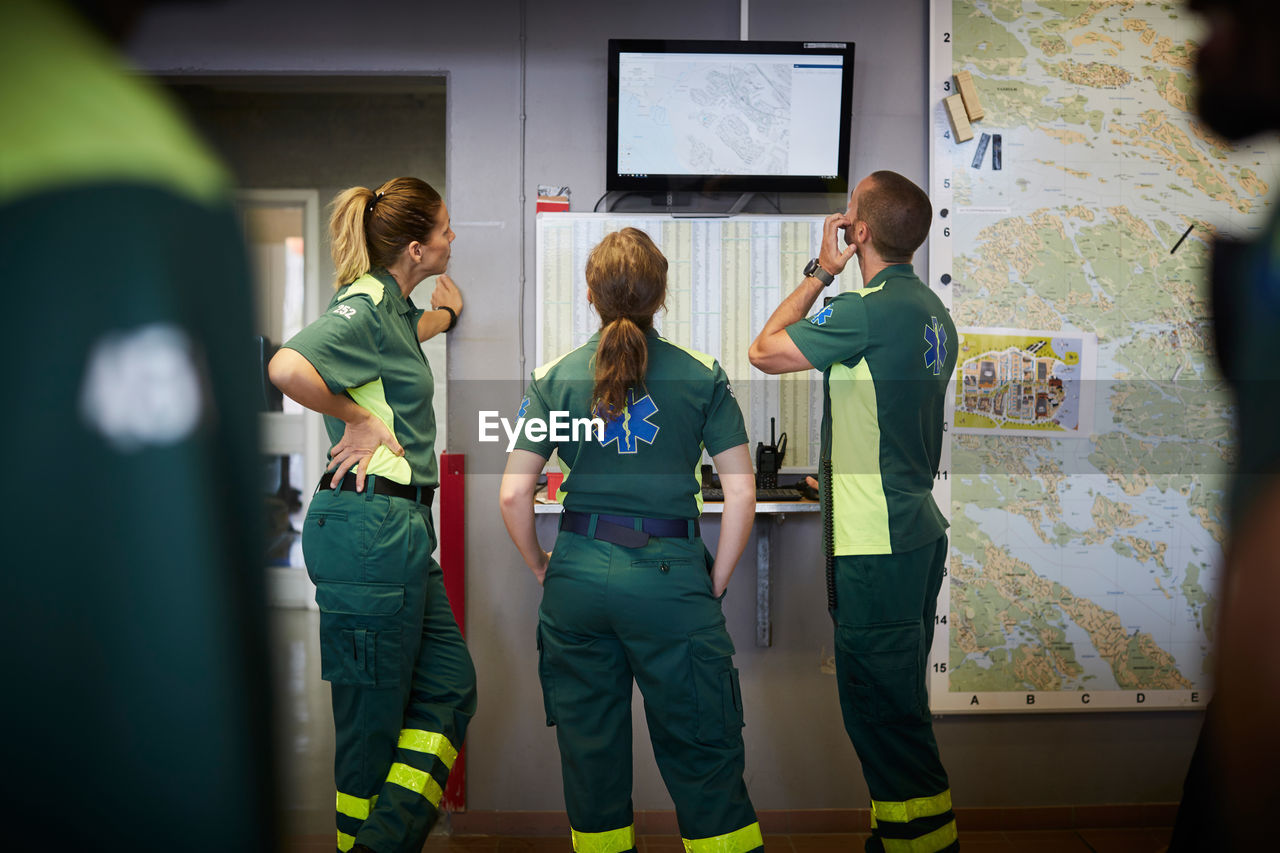 Male and female paramedics discussing while looking at screen in hospital
