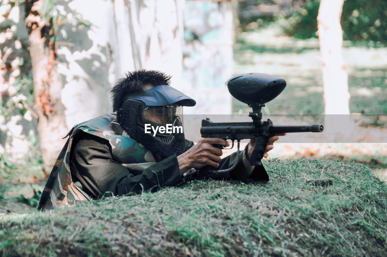 Rear view of man with paintgun on field