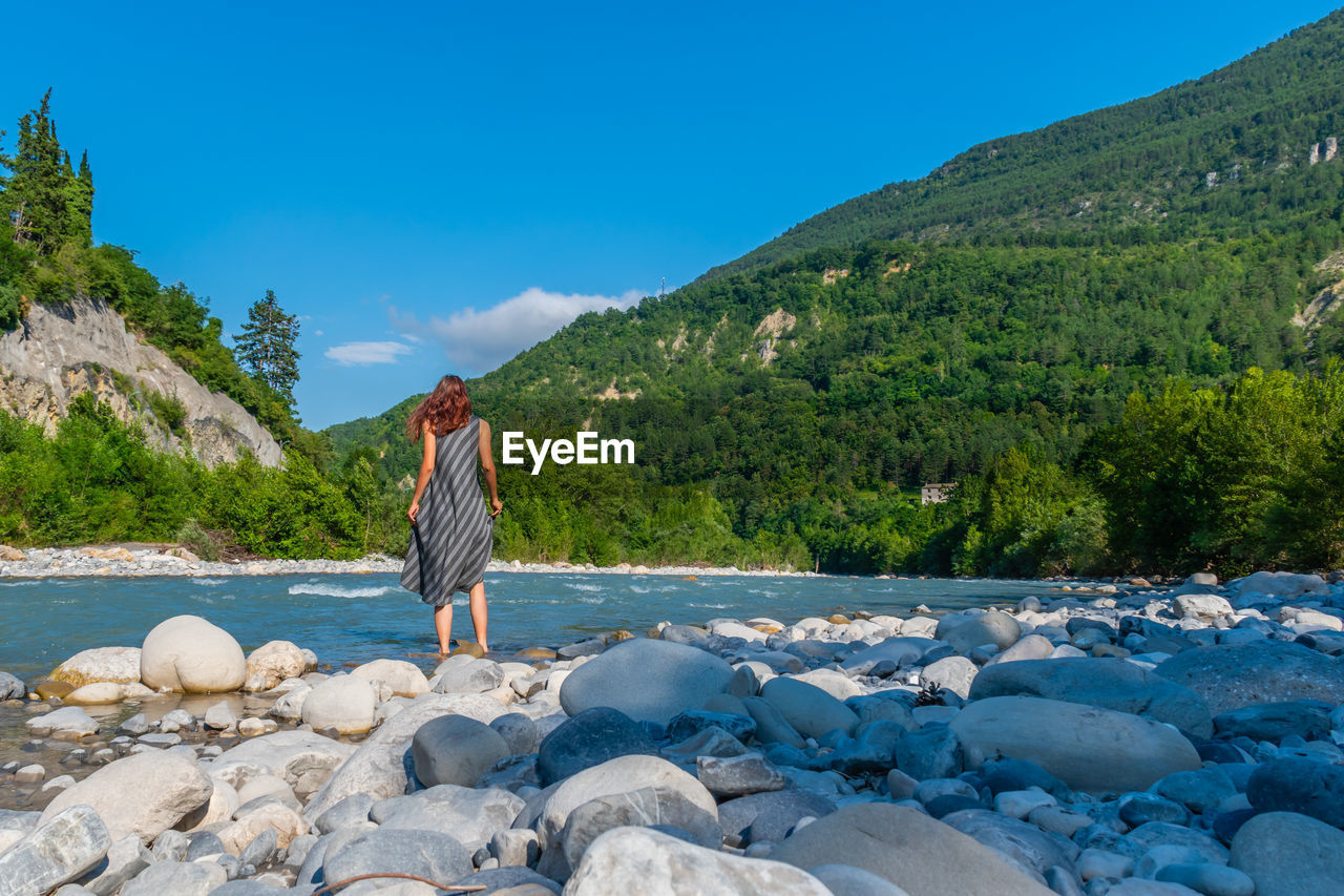 REAR VIEW OF MAN LOOKING AT SEA AGAINST SKY