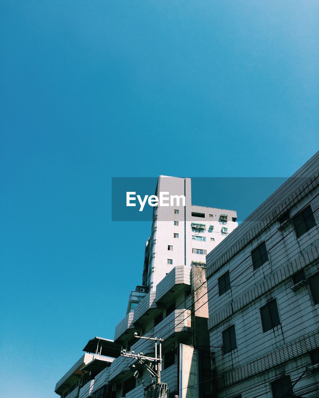 LOW ANGLE VIEW OF MODERN BUILDINGS AGAINST CLEAR BLUE SKY