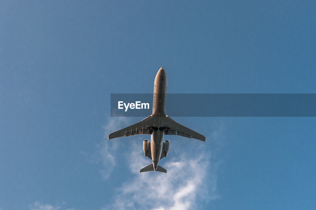 LOW ANGLE VIEW OF AIRPLANE AGAINST BLUE SKY