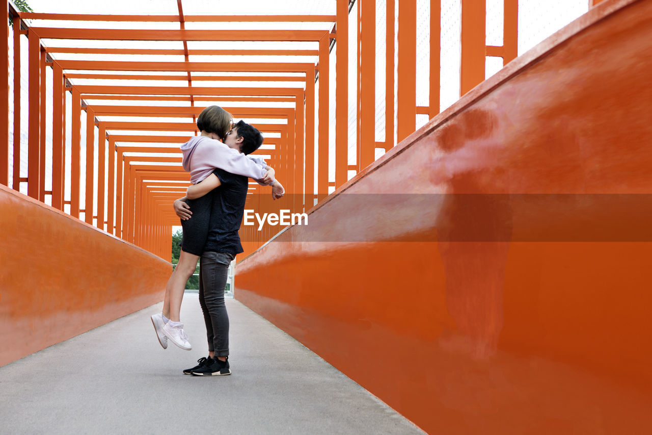 Teenage couple kissing on orange bridge