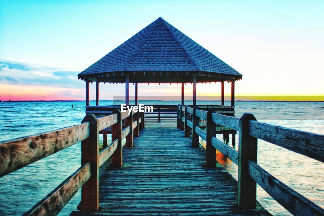 WOODEN PIER ON BEACH AGAINST SKY