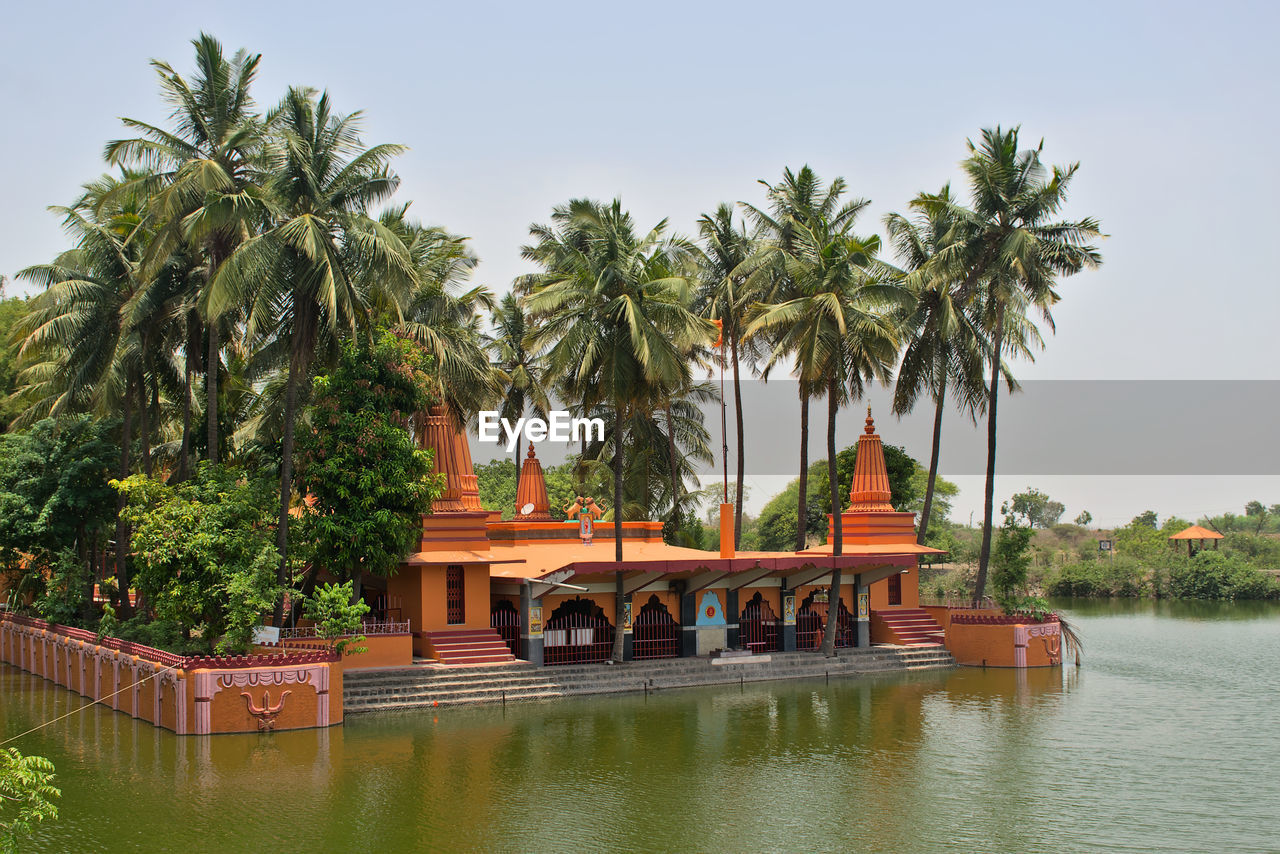 water, tree, tropical climate, palm tree, plant, architecture, nature, travel destinations, built structure, vacation, sky, travel, tourism, religion, river, reflection, building exterior, building, outdoors, no people, coconut palm tree, day, nautical vessel, environment, beauty in nature, tradition, transportation, history, holiday, trip, tranquility, temple - building, the past, landscape, belief, city