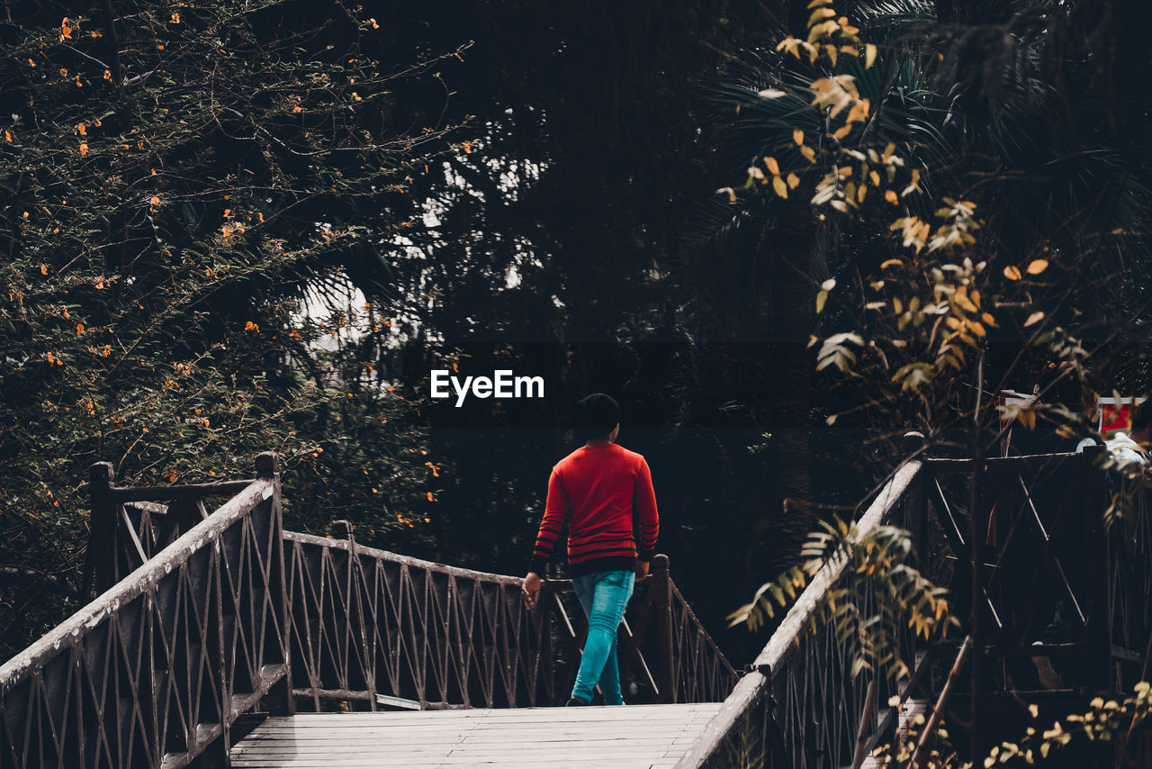 Rear view of woman walking on footbridge