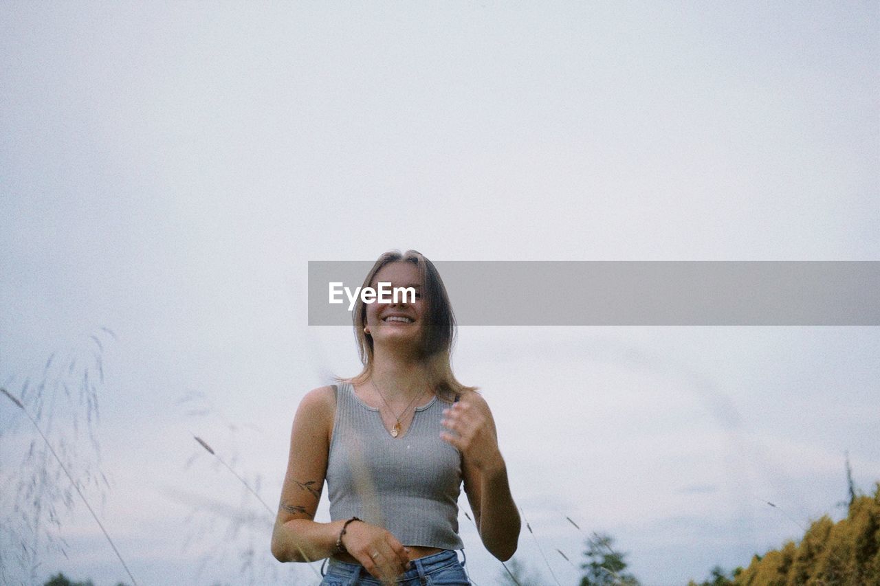 Portrait of young woman standing against sky