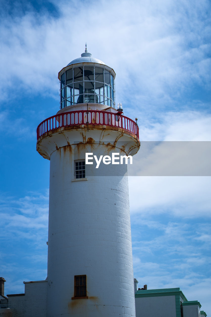 Low angle view of lighthouse by building against sky