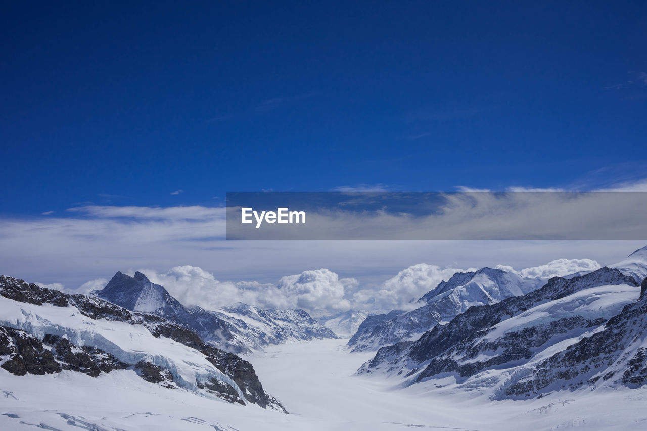 Scenic view of snowcapped mountains against blue sky