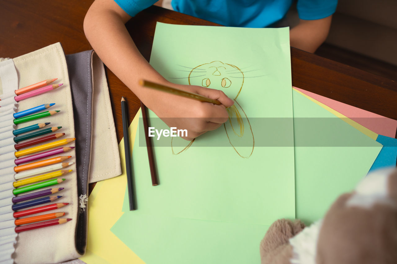 Midsection of boy drawing on paper