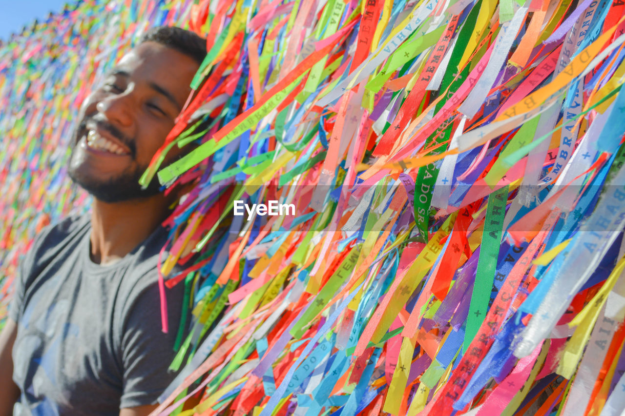 Smiling young man by colorful prayer ribbons