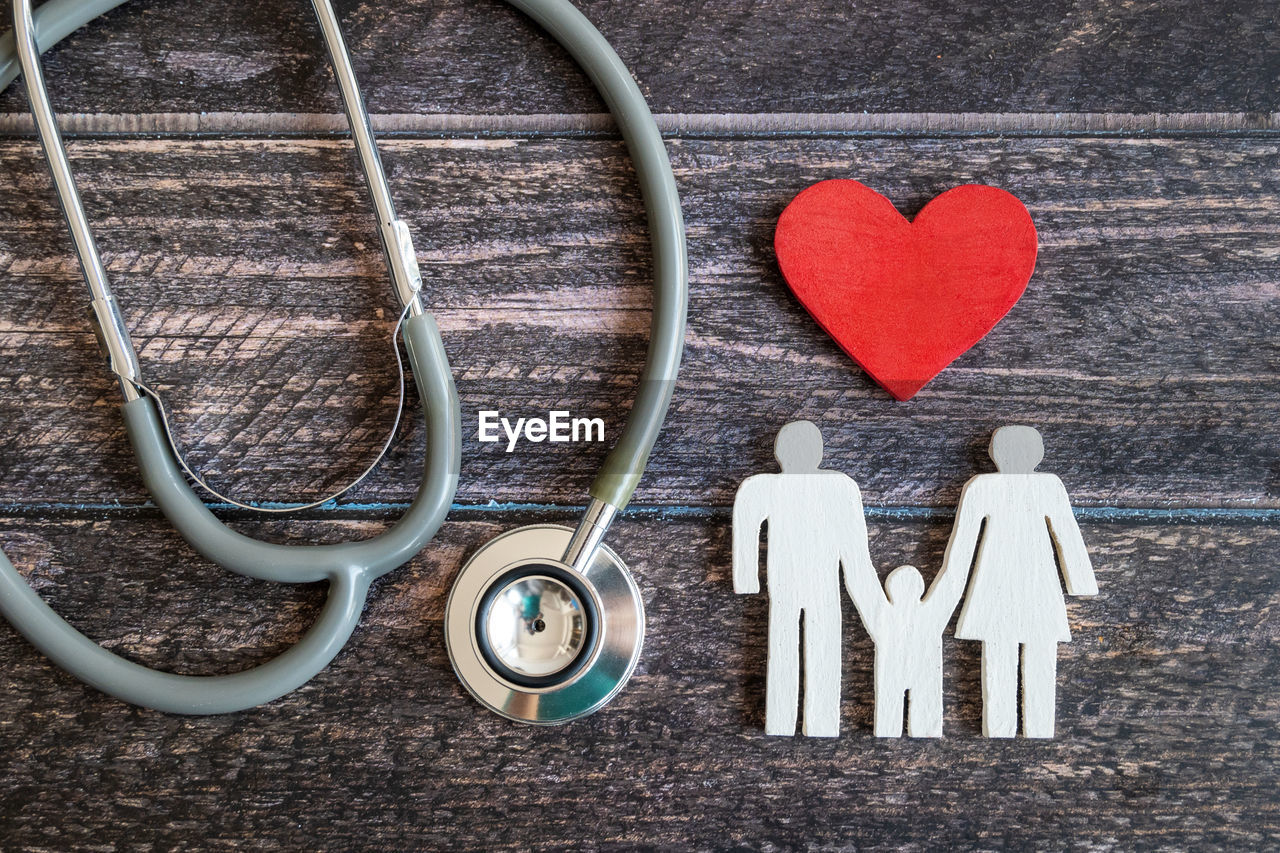 Close-up of figurine with stethoscope and heart shape object on table