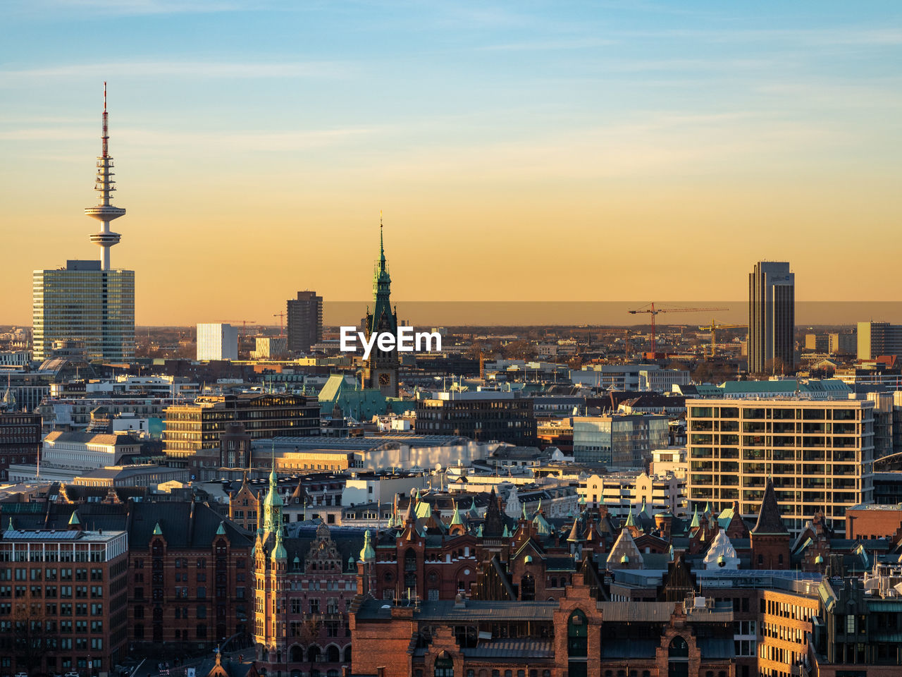 Modern buildings in city against sky during sunset