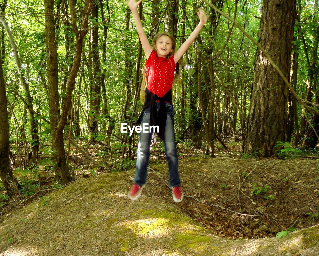 Full length portrait of girl jumping in forest