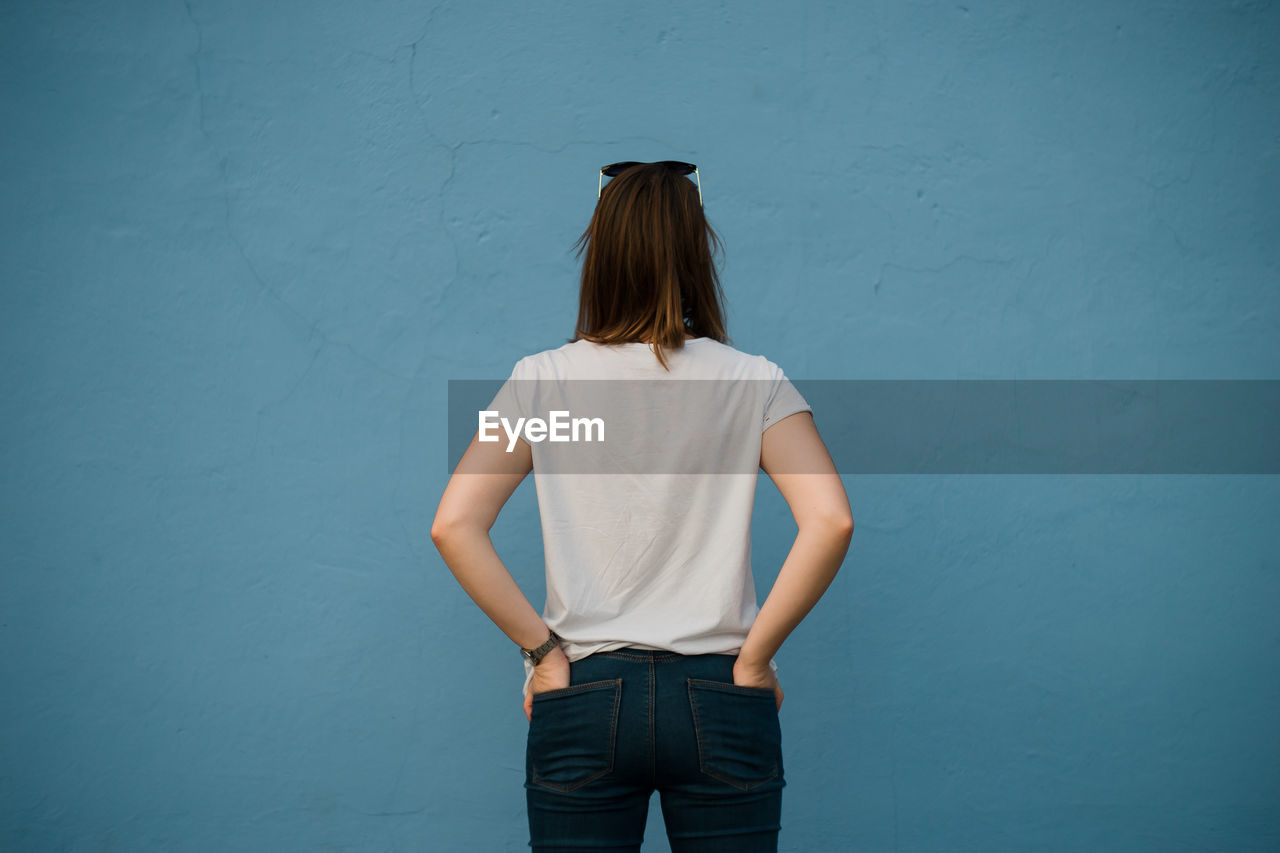 Rear view of woman standing against blue wall
