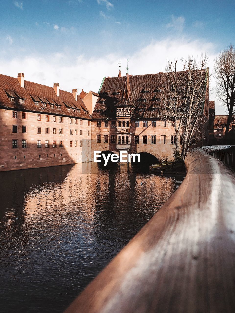 Bridge over river by buildings against sky