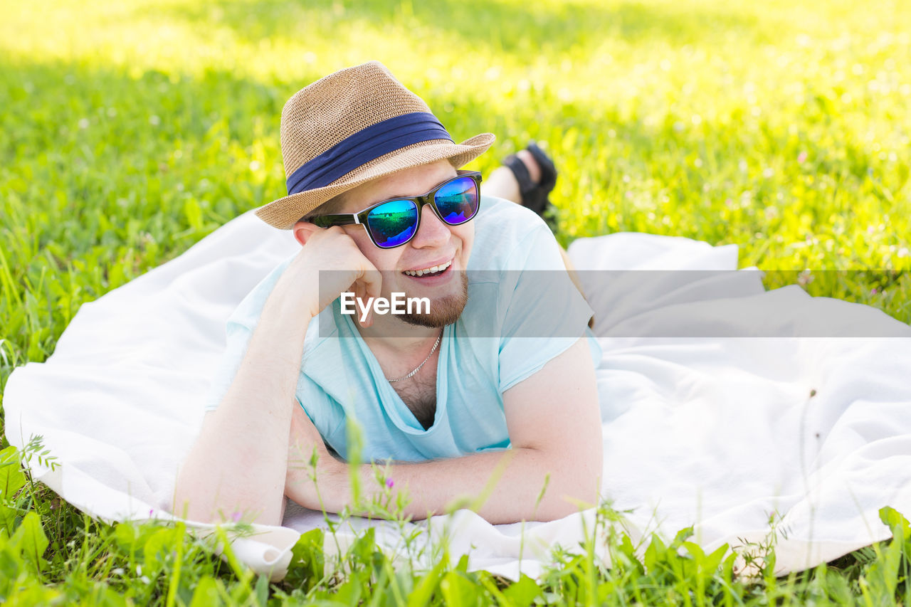 MAN WEARING SUNGLASSES LYING DOWN ON GRASS