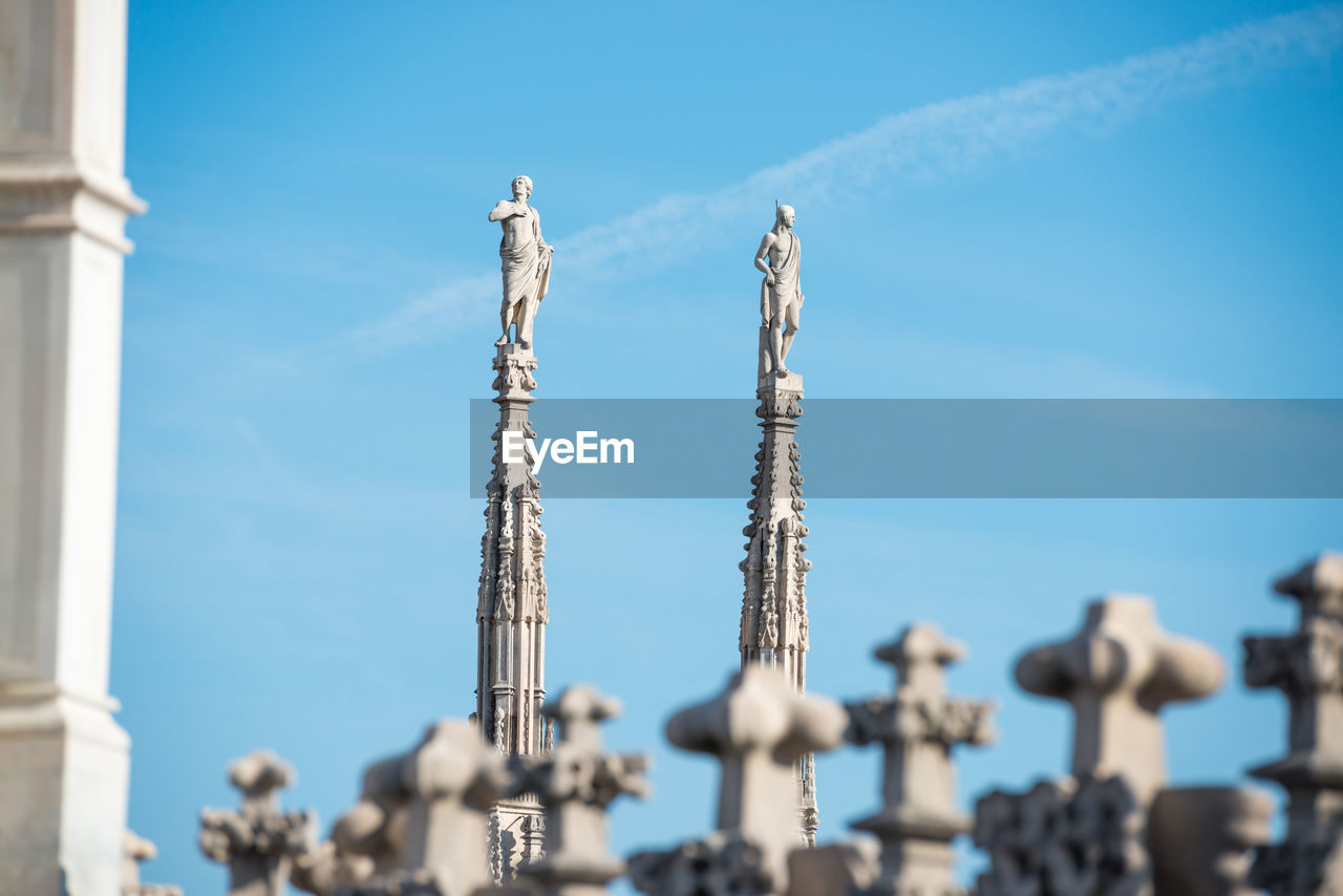 View to spires and statues on roof of duomo through ornate marble fencing. milan, italy