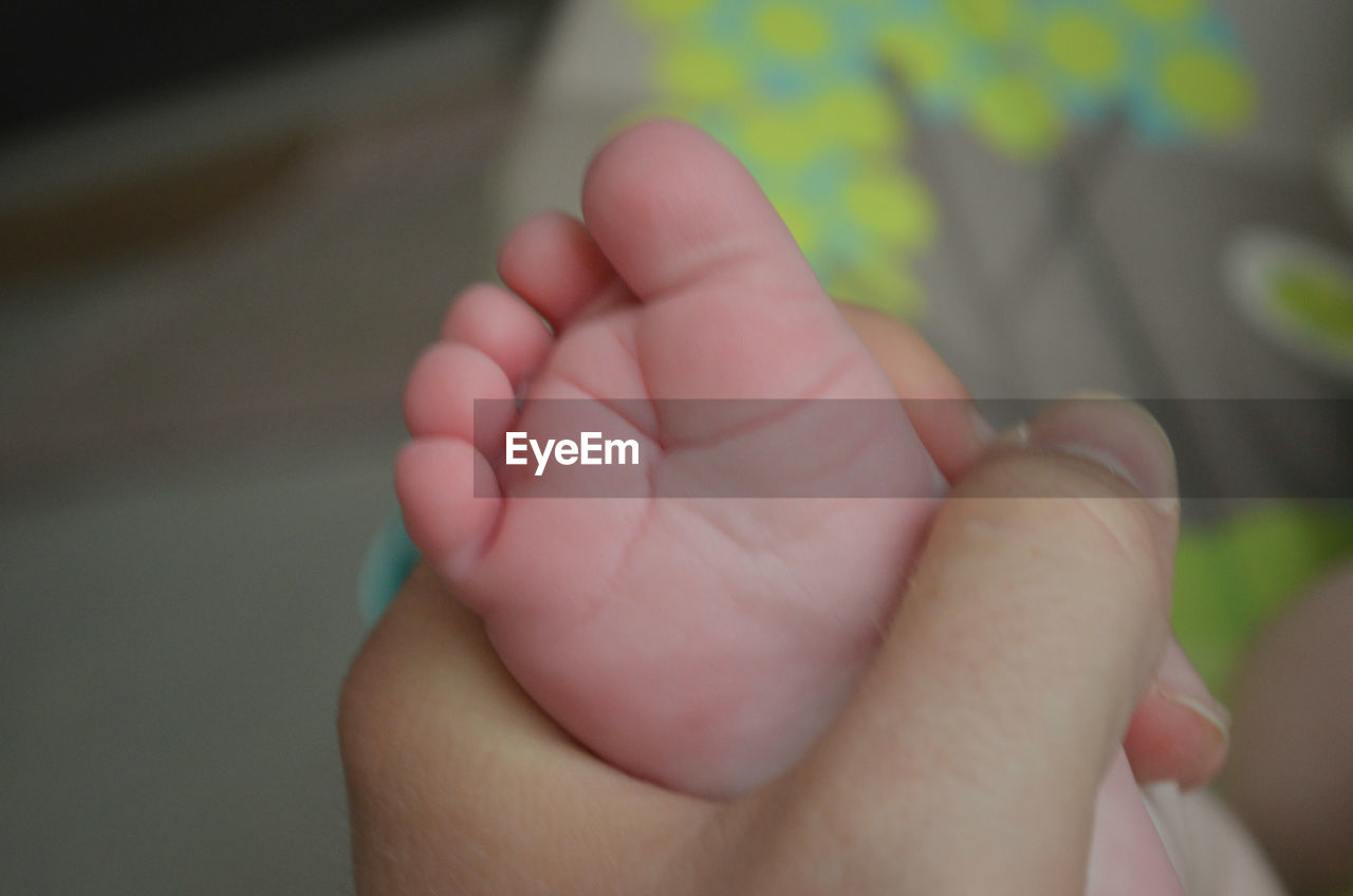 CROPPED IMAGE OF YOUNG WOMAN HOLDING BABY FEET