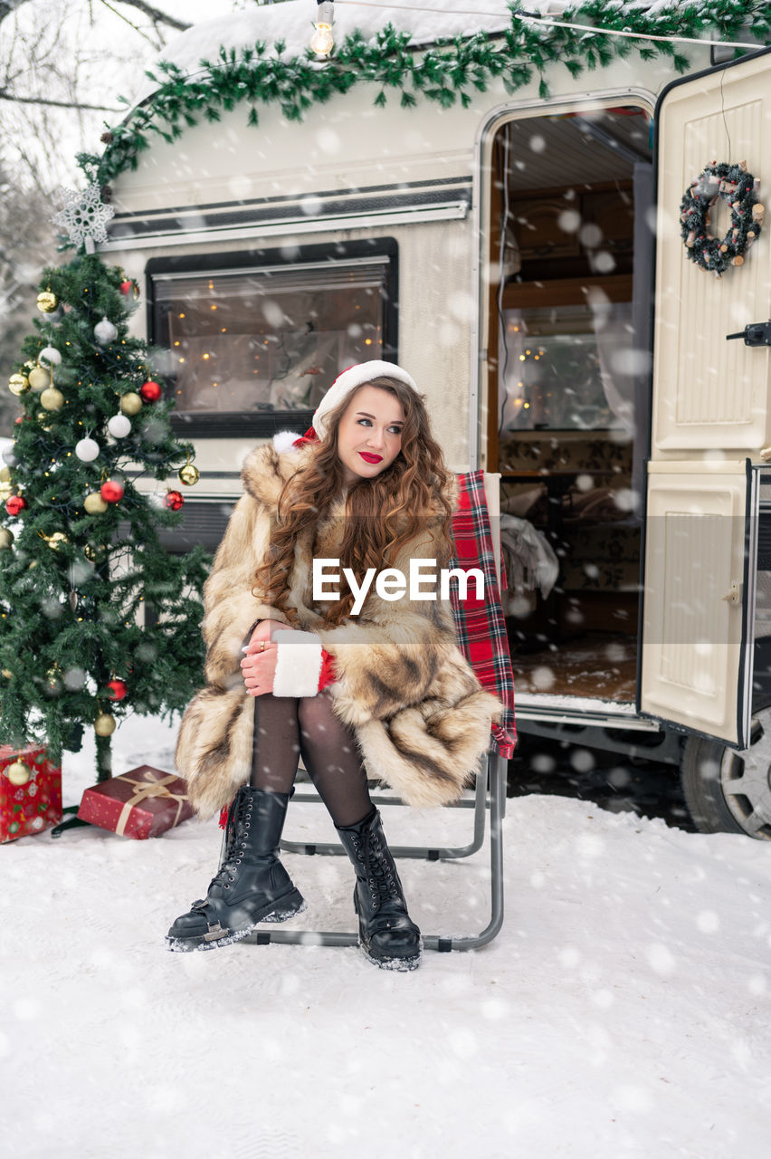 full length of woman sitting on snow during winter