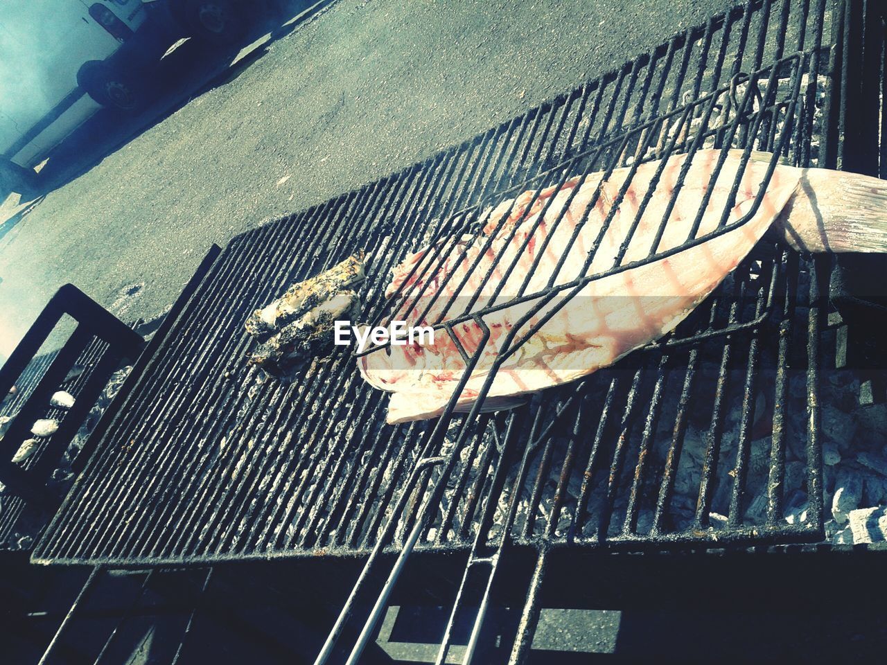 barbecue grill, barbecue, food and drink, high angle view, fish, grilled, day, preparation, outdoors, food, seafood, no people, metal grate, healthy eating, close-up, water, freshness
