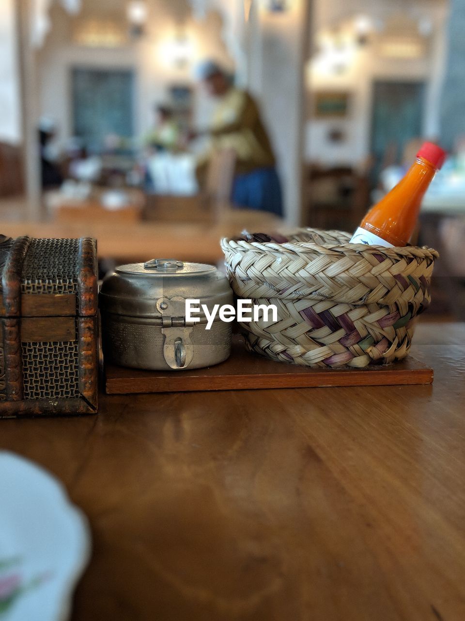 Close-up of ketchup bottle in wicker basket on table at restaurant