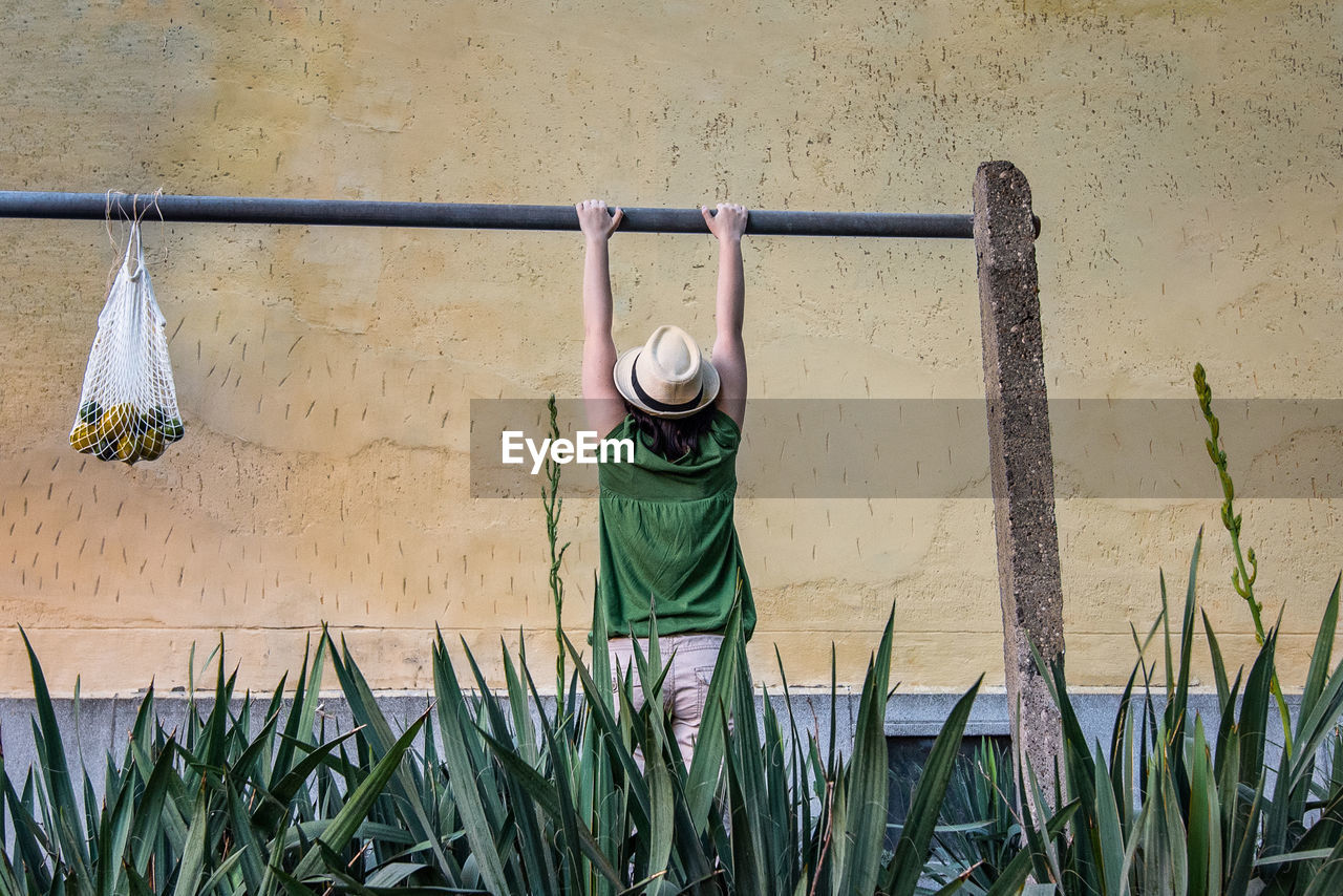 Rear view of woman hanging against yellow wall