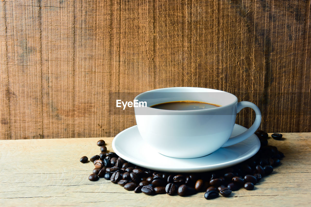 Close-up of coffee cup with beans on table