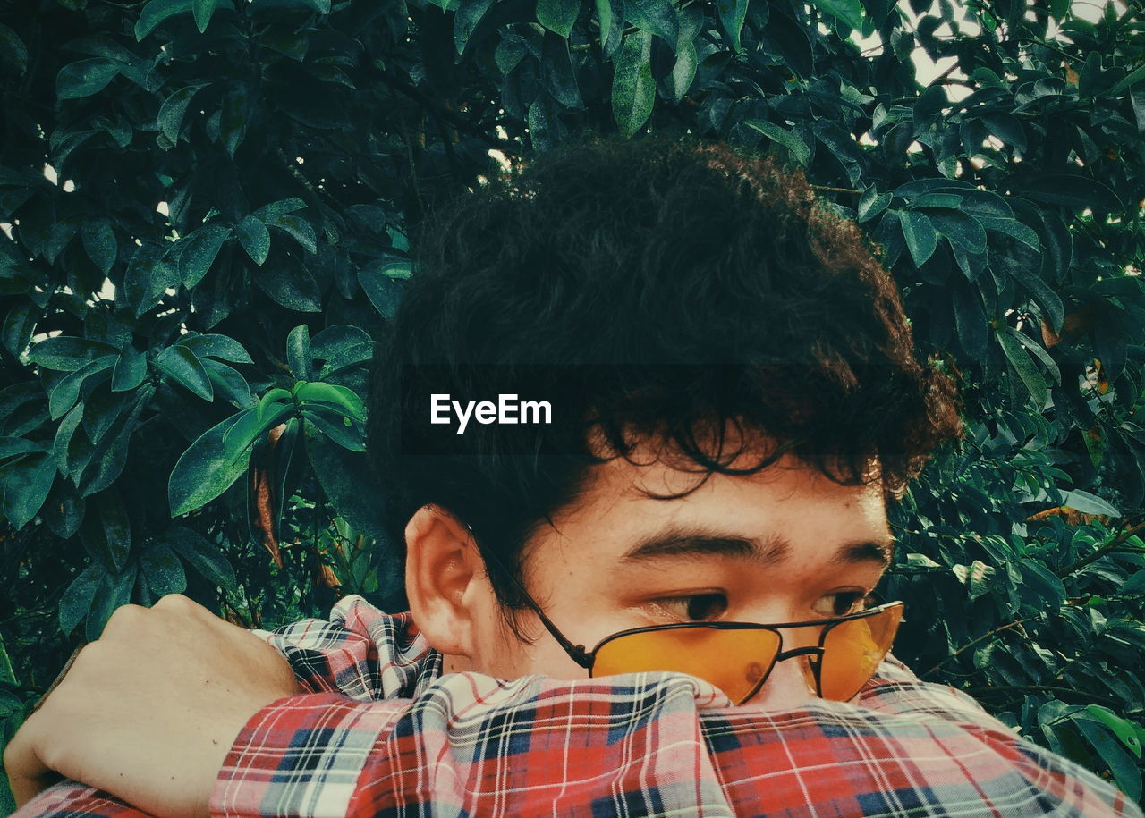 Close-up of man wearing sunglasses against plants