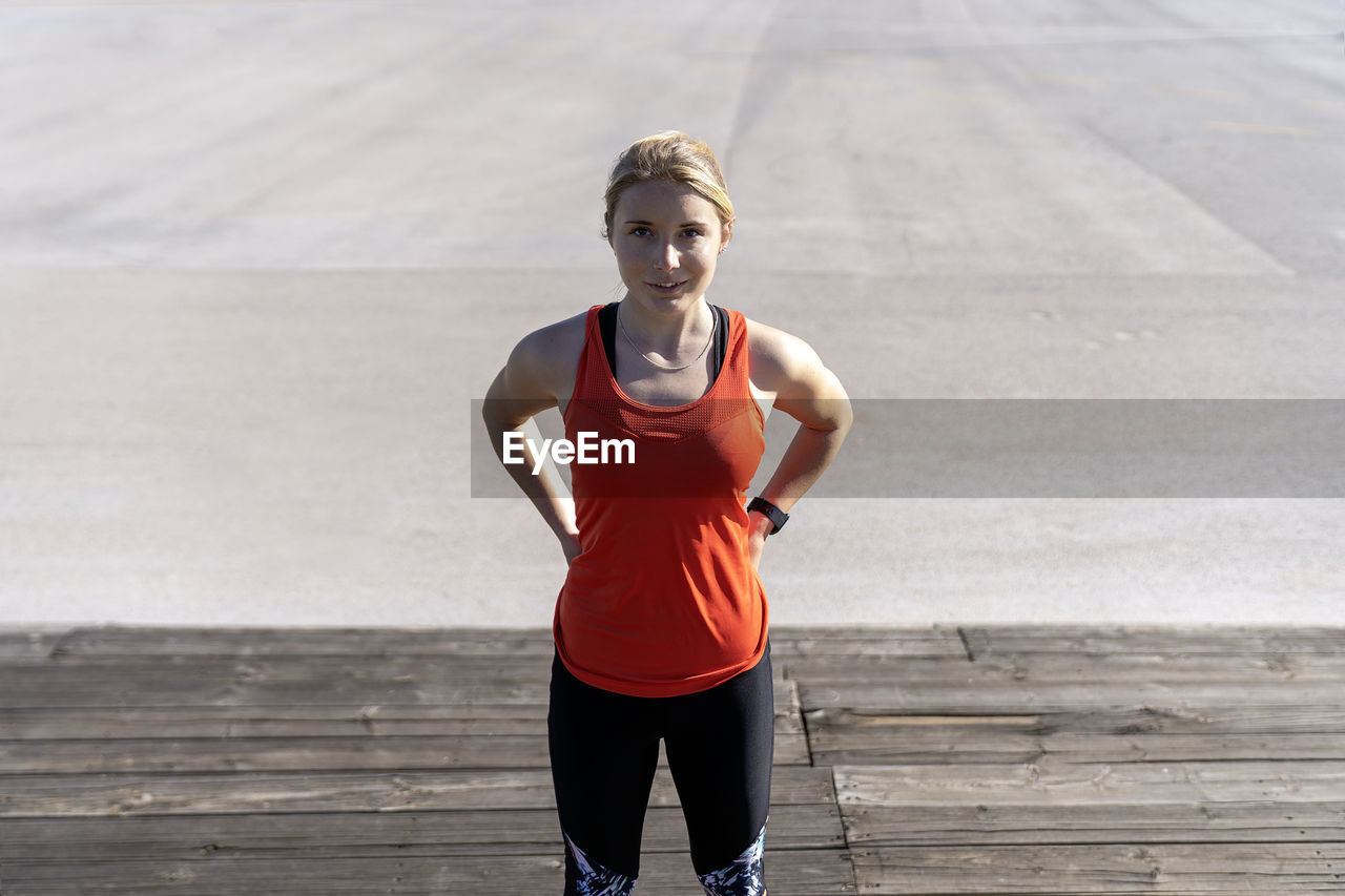 Female jogger standing on pier during sunny day